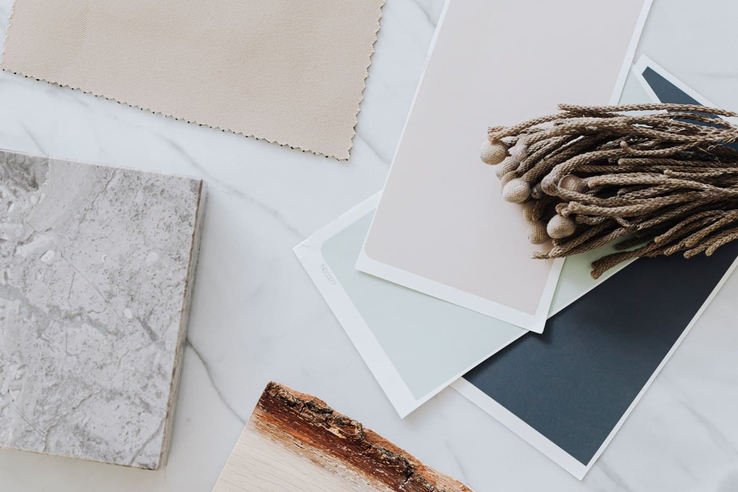 Échantillons de pierre, de bois, de textile et de finis dans une palette neutre.