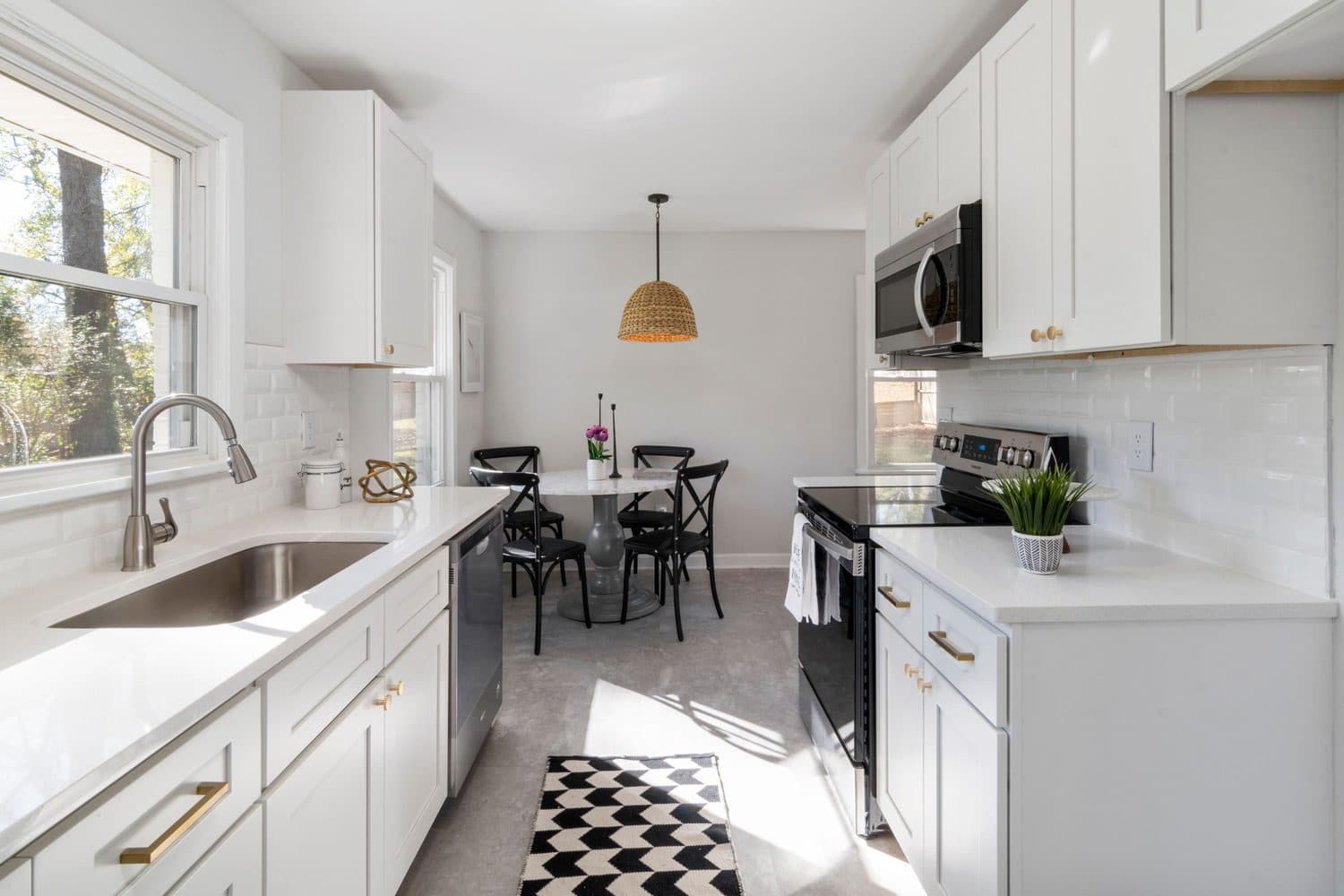 Cuisine résidentielle lumineuse avec armoires blanches, comptoirs clairs et plancher gris.